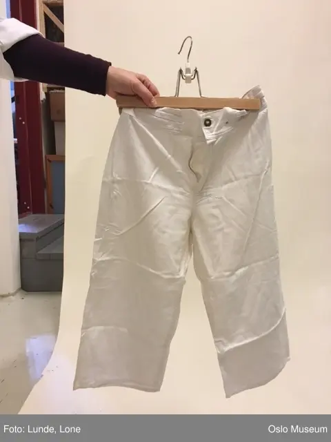 Jakke og bukse i gråsort ullstoff, blåskjorte i bomull og sort lue med brem. Skjorte og halvlange bukser.