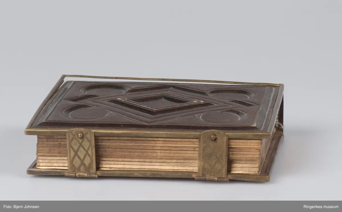 Reliffmønster på begge permer, parallellogram med fire sirkler i ytterkant.