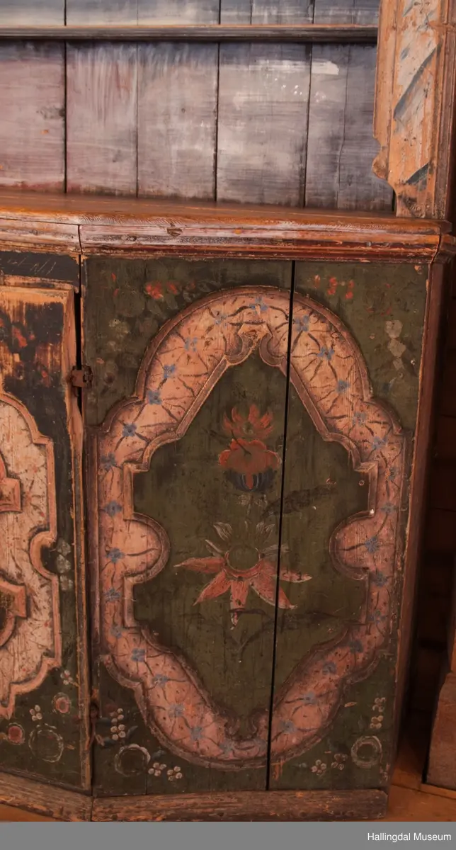 Marmorert toppstykke over felt med fem fyllinger.  Feltet grønnmalt med røde og hvite blomster.  Fyllingene, hvit bunn, sortmalte bokstaver og tall:  Anno 1796 H. Sata.  Overskapet har to hyller med lister og en smal hylle med profilert kant.  Bakveggen hvitmalt med rester etter mørkere undermaling, sideveggene marmorert.  Underskapet tredelt, fremspingende midtparti som er dør.  Fyllinger på de tre delene.  Grønn bunnfarge.  Slitt rosemaling, hvitt og rosa.  Profilert gulvlist.  Nøkkelhull med beslag og defekt lås av jern.  En hylle innvendig.