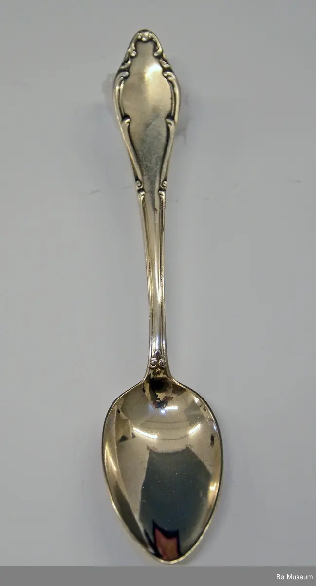Liten sølvskje, dessertskje - 1 av 6 - i etui. I etuiets lokk er det festet en lapp med 2 sikkerhetsnåler. Tekst: "Hans Kleppen - Springlauf ....... 2 Preis(?)". Kan være fra Klosters i Sveits i 1928 - der kom han på 2. plass.

Stempel: (hus) WELLNER (90) - 21
Mønster: "Mozart"