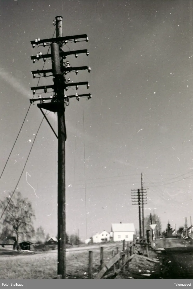 Telefonstolpe med stolpestol og en rund høy fordelekasse. Ottestad ca 1960