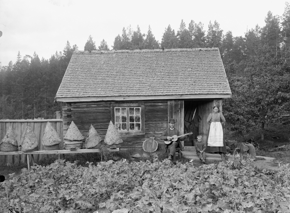 Arbetaren Karl Albert Johansson med hustrun Anna Lovisa Karlsdotter på trappan till torpet Östanstorp under Ramsefall i Södra Vi sn. Mellan makarna sitter deras dotterson Axel.