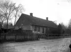 Hus med liten trädgård och uthus, en pojke står framför huset, vy 1920 på asken
	Kraftig metallutfällning.