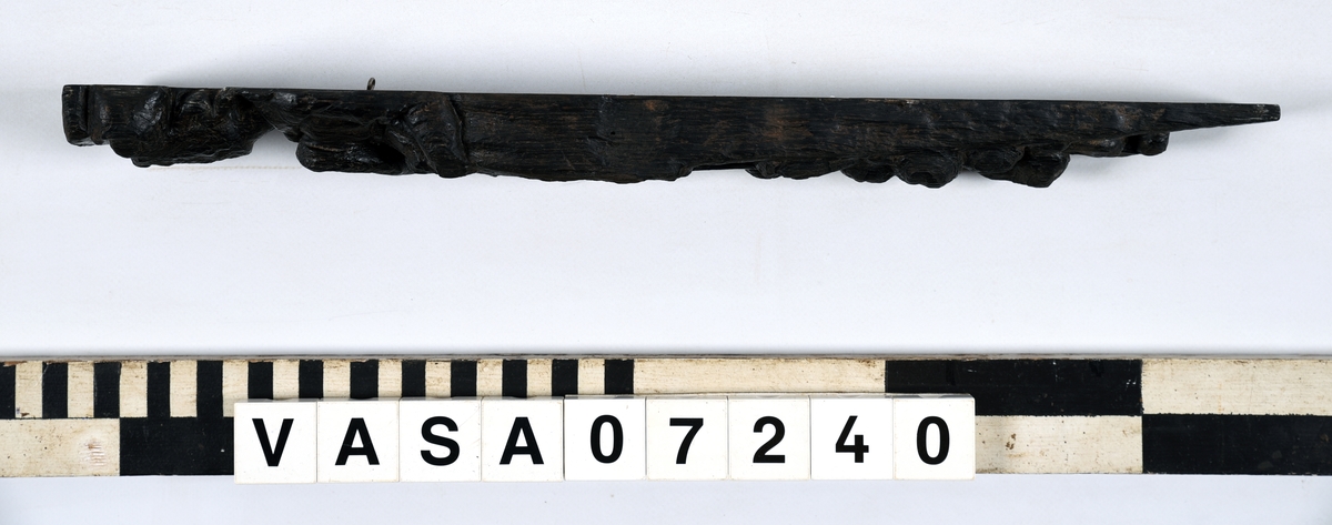 Hermpilaster.

Liten pilaster i form av en karyatid, med långt böljande hår under joniskt kapitäl.

Huvudet är vridet en aning åt höger. Med vänster hand hålls manteln samlad. I höger hand håller figuren en frukt eller dylikt framför bröstet. Pilasterskaftet är prytt med stora frukter och blad, fasthängande vid en stängel som delvis täcker det nedåt avsmalnande skaftets ramverk. Baksidan är slät.

Skulpturen är välbevarad, förutom ansiktet som är kraftigt slitet.

Fyra stycken spikhål, en övertäckt med en plugg.


Text in English: Sculpted small pilaster with a Caryatid with long wavy hair beneath an Ionic capital.

Its head is turned slightly to the right, its left hand holds its gathered mantle. Its right hand holds fruit or the like in front of its brests. The shaft of the pilaster is decorated with fruit and large leaves hanging from a stalk, which partly cover the framing of the tapering shaft. Its back is flat.

The sculpture is somewhat worn, its facial expression has been obliterated.