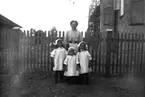 En kvinna och tre flickor.
Hedvig, Brita och Ingeborg Johansson med modern Emilia Johansson.
Bilden kan vara tagen på gården till Nobelgatan 8 i Örebro (jämför med bild 10, 11, 19).