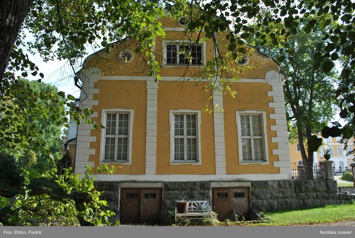 Livstallet och Vagnsflygeln är de två senast tillagda flyglarna i herrgårdsmiljön. Vagnsflyglens uppförande påbörjades 1903 och byggnaden stod klar 1905. Redan året efter började ett rum i byggnadens västra del att inredas för gårdens bibliotek. Av någon anledning bestämmer man sig istället för att flytta gårdskontoret från Södra flygeln till Vagnsflygeln. Vid samma tid som gårdskontoret flyttar in i Vagnsflygeln köps en personbil in till gården och 1912 inreds den östra delen av Vagnsflygeln som ”bilstall” och en ny större port sätts in.

På ett äldre fotografi på vagnsflygelns södra fasad syns ett takfönster i byggnadens västra del. Fönstret har fungerat som ljusinsläpp till vinden, trapphuset och gårdskontoret. Från gårdskontoret hämtade gårdens arbetare ut sin lön från bokhållaren och inspektören. Bokhållaren hade sin bostad i ett rum ovanför gårdskontoret. I vagnshallen stod gårdens finare vagnar. Förutom bokhållarens bostad fanns, på vinden, två andra lägenheter.

Byggnaden inrymmer:
1 st lägenhet för åretruntboende.
En utställningshall.
Tidigare mangelbod, nu linneförråd för uthyrningsrummen.
Panncentral till Vagnsflygeln och Norra/Södra flygeln.
Garage och förrådsutrymmen.