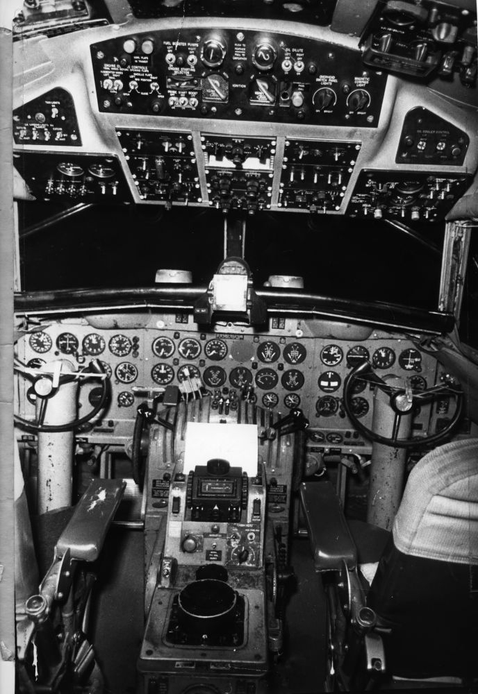 Lufthavn/Flyplass. Cockpiten til et fly, Convair 440. Instrumentpanel og tak dekket av klokker med visere, throtler og sikringer. Setene til pilotene med stkkene foran.