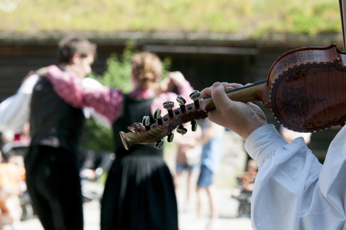 Dansende par og hardingfele i Telemarkstunet på Norsk Folkemuseum