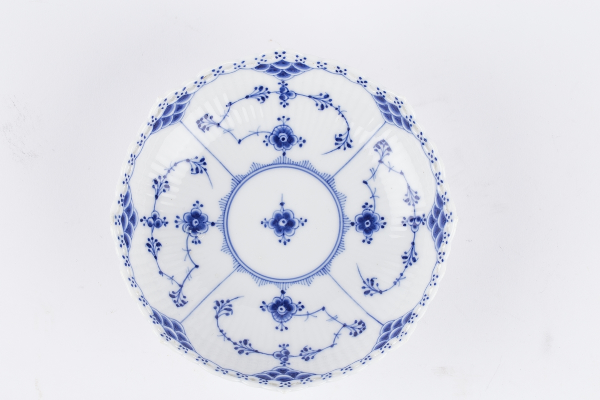 Ovalt stettfat i riflet gods med blått musselmalt mønster med gjenombrudt blondekant. Fabrikkmerket med Royal Copenhagens tre bølger samt malersignatur.