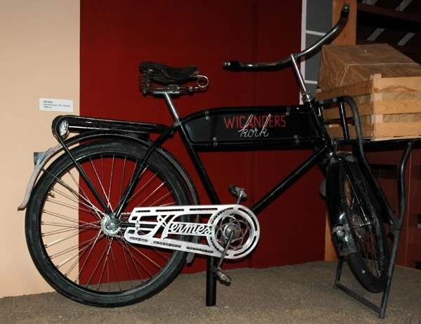 Svart paketcykel, märkt: "WICANDERS kork" i röd och vit text, med stöd under pakethållaren fram. Märke: "Hermes".
AB NYMANS VERKSTÄDER UPPSALA".