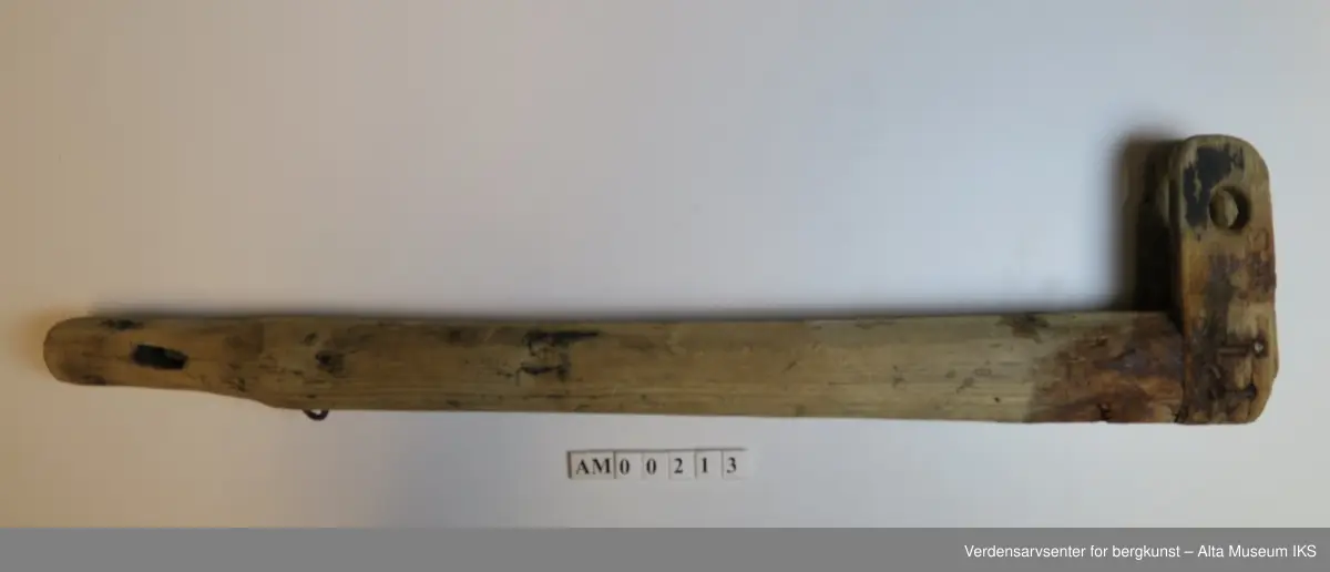 Avlang trepinne med to mindre gjennomborede trestykker stiftet med jernstifter i en ende, med et boret hull i den andre enden.