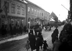 Gatubild, häst & bil kortege (begravning?) mycket folk kantor gatan Ahlgatan
	Metallutfällning, repor.