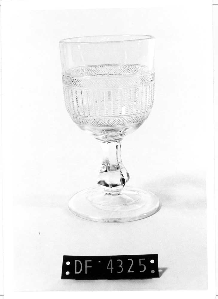 Vin- eller ølglass.

Klokke med presset bord (3,8 cm). Fasettert stett, baluster. Fot med konsentrisk "trapp".