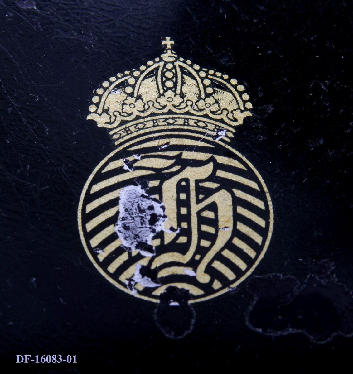 Symaskin på tresokkel, med tilhørende lokk med lås og håndtak. Symaskinen er utstyrt med lampe og  elektrisk motor, festet på baksiden med ledning og pedal.