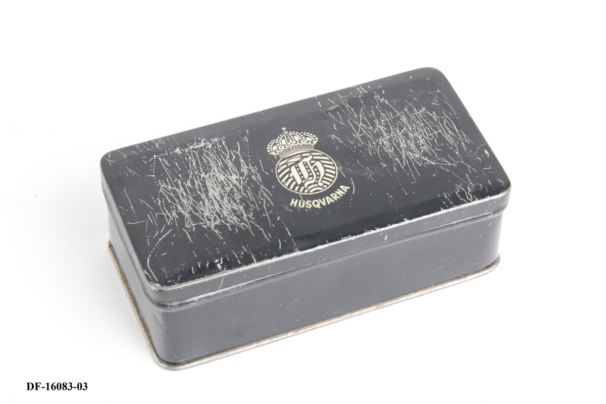 Symaskin på tresokkel, med tilhørende lokk med lås og håndtak. Symaskinen er utstyrt med lampe og  elektrisk motor, festet på baksiden med ledning og pedal.