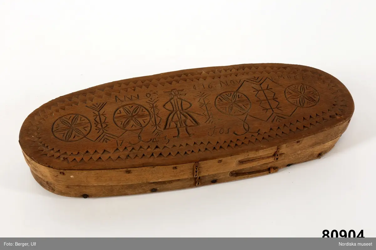 Inventering Sesam 1997-1998:
L 40, B 15, H 6 cm
Ljusask, oval, Botten och lock av barrträ med svep av lövträ, med falsar. Bottensvepet fästat med järnnubbar,  lockets svep fästat med dymlingar av trä. Hopfästning av svepen med rottågor, kedjesöm, två rader. Skuren ornamentik på locket, karvsnitt och uddsnitt, föreställande  människa. På locket inskuret "ANNO D 16 NOVEMBER 1743  JOS".
Begagnad vid upphämtandet av julljusen för kyrkans behov inom den rote som Näs by tillhört.
AMB

