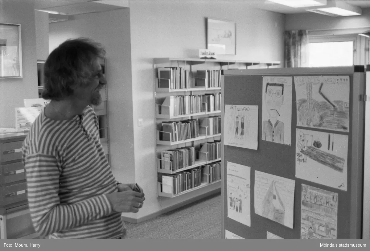 Ungdomsförfattaren Lasse Ekholm besöker Kållereds bibliotek, år 1984. "Författaren Lasse Ekholm studerar Kållereds-skolornas illustrationer till personerna i hans ungdomsböcker."

För mer information om bilden se under tilläggsinformation.