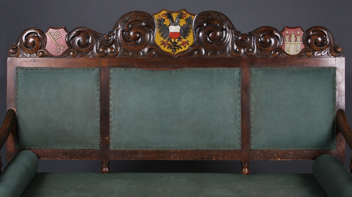 I utskjæringene over tre felter i sofaens rygg er det våpenskjold (byvåpen). Det venstre har en nøkkel, det i midten er Lübecks dobbeltørn, det høyre har en borg med tre tårn og en port. Over to av tårnene er det en stjerne, over tårnet i midten et kors. Rundt våpenskjoldene (byvåpnene) er det ranker og blad. I midtstykket mellom sofaens frontbein er det også ranker, og på armlene er det blad.