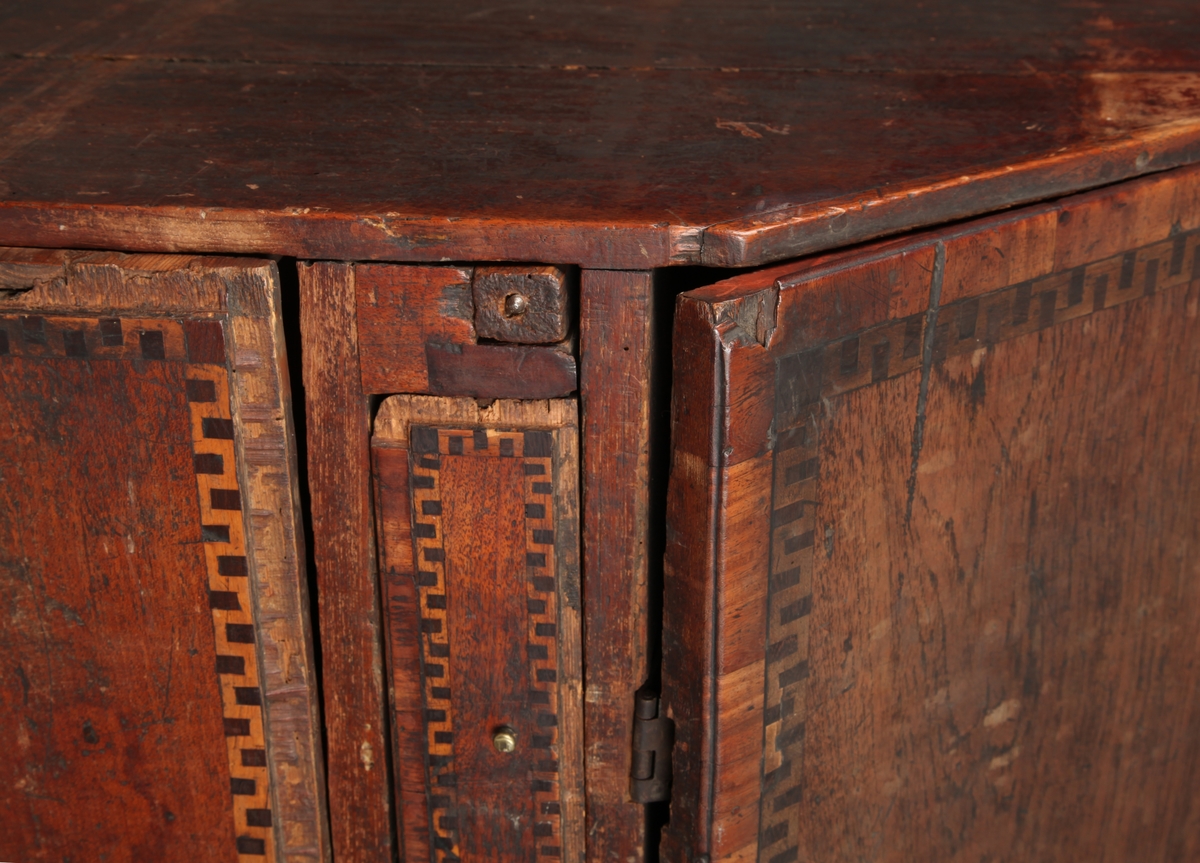 Lyst, rektangulært "slangebuktende" båndt med mørke felter i en bord langs tre sider av skriveplatens front og langs alle sidene av de tre store skuffene og den smale store skuffen.