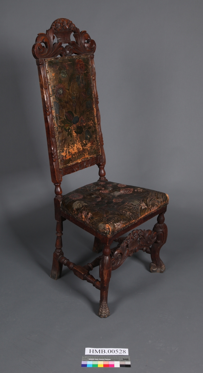 Stol med sete og rygg av gyldenlær og med dreiete buete bein. Mellom bein i front er det et utskåret stykkw.