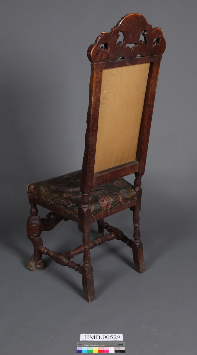 Stol med sete og rygg av gyldenlær og med dreiete buete bein. Mellom bein i front er det et utskåret stykkw.