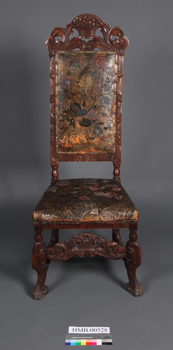 Stol med sete og rygg av gyldenlær og med dreiete buete bein. Mellom bein i front er det et utskåret stykkw.