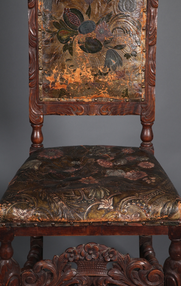 Stol med sete og rygg av gyldenlær og med dreiete buete bein. Mellom bein i front er det et utskåret stykkw.