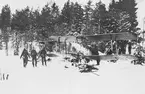 Två norska, nödlandade militära flygplan Tiger Moth på ett fält, vintertid. Militärer i arbete vid flygplanen.