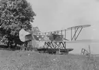 Flygplan FVM S 21 står uppställd på en vagn vid Roxens strand. Vid prov av flottörer. Flygare på plats i flygplanet.