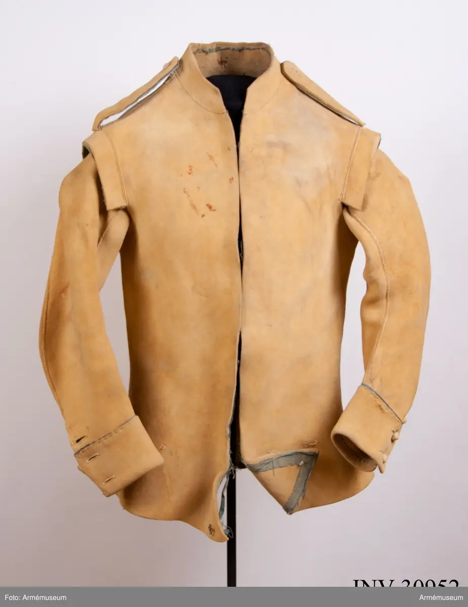 Kyller av gul älghud med blå linneband som kantning på insidan. Lätt utsvängt nertill med litet skört bak. Uppvik framtill, axelkarmar och låg krage.  Kragens linneband är i dag i upplösning och bara några trådar finns kvar.
Helt framtycke, och delat bakstycke samt två separata sidstycken. Sidsöm under ärmen.
Formade tvåsömsärmar med ärmuppslag. Ärmuppslagen har blå passpoal och sprund som knäpps med 3 koniska knappar klädda med sämskskinn i samma färg. Ett fjärde knapphål som är igensytt talar om att plagget blivit omsytt vid något tillfälle. En rad hål efter stygn på insidan av höger framstycke visar att plagget har haft en knappstolpe/underlott.
Axelklaffar fodrade med blått linne som knäpps vid kragen med samma knappar som ovan.
Plagget knäpps kant i kant mitt fram med 12 stycken hyskor och hakar av metall. Alla sömmar är sydda med oblekt lintråd.
Märkt inuti ryggen med "N 2".