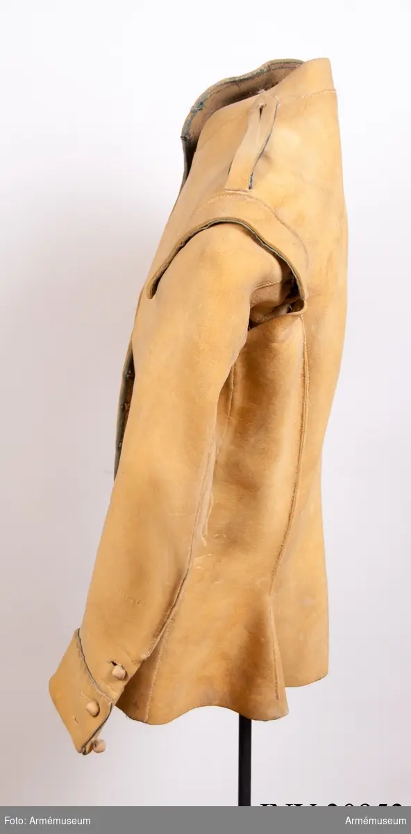 Kyller av gul älghud med smala blå linneband som kantning på insidan samt som passpoal vid övre kant av ärmuppslagen.
Helt framstycke med utsvängt kort skört med uppvik framtill, samt bakstycke med mitt-bak-söm och två sidstycken. Sidsöm under ärmen. Formad tvåsömsärm med ärmuppslag. Ärmuppslagen har sprund som knäpps med 3 koniska älghudsknappar i varje sida, även om det är utskuret 6 knapphål i höger ärm och 5 i den vänstra. De knapphål som inte används är ihopsydda. Liten axelkarm, samt axelklaffar på båda sidor som är fastsydda vid axelsömmen samt knäpps med älghudsknapp vid halsen. Knapp saknas på vänster axel.
Låg ståndkrage som har varit kantad på insidan med blått band. Detta saknas i dag.
Plagget knäpps kant i kant med 12 stycken hyskor och hakar mitt fram. Alla sömmar är sydda med oblekt lintråd.
Märkt inuti ryggen "No 1".
Kyllret skiljer sig något från samtida kyller av samma modell genom att de blå banden är smalare.