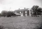 Mangårdsbyggnad med litet uthus och gärdsgård.