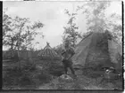 John Bauers Lapplandsresa sommaren 1904. Ett sameläger i Ripainenjoki. En man står framför en kåta.