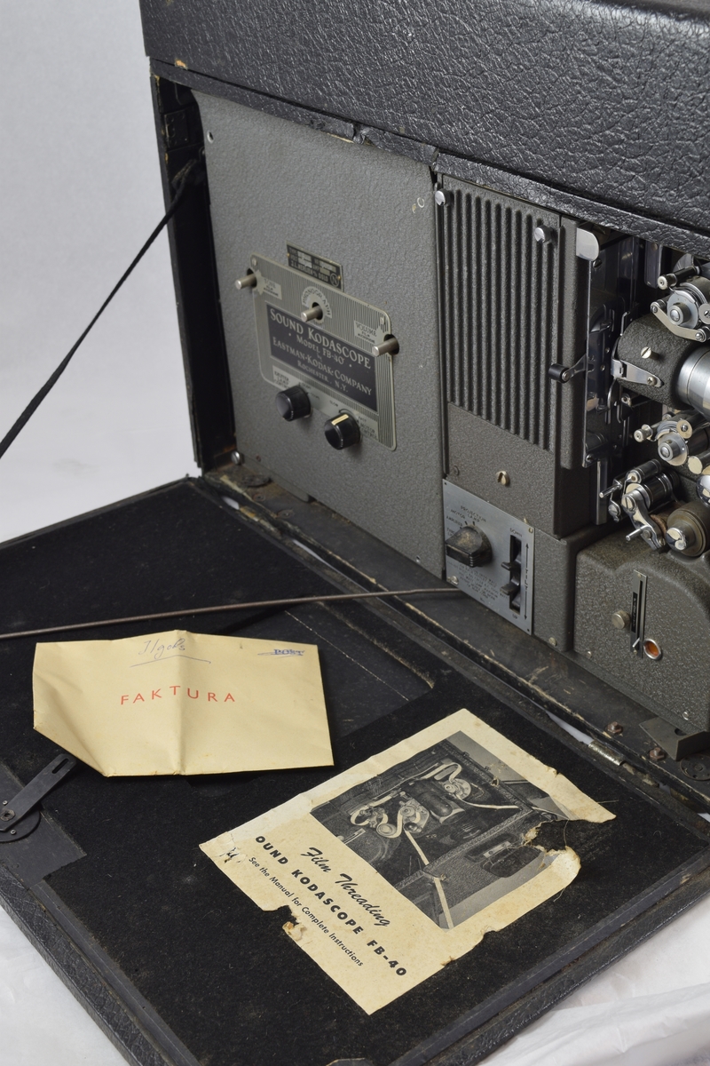 Filmfremviser til filmruller. Filmen tres gjennomapparatet som vist på arket på eskens innside. Rektangulær koffert rundt apparatet med luker som kan åpnes der det er behov. (Høyttalere kommer i tillegg - se referanser.)
