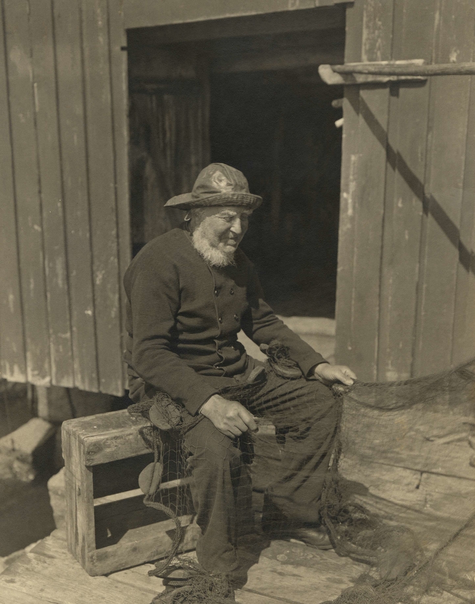 En gammal fiskare som sitter och lagar nät i Smögen Bohuslän