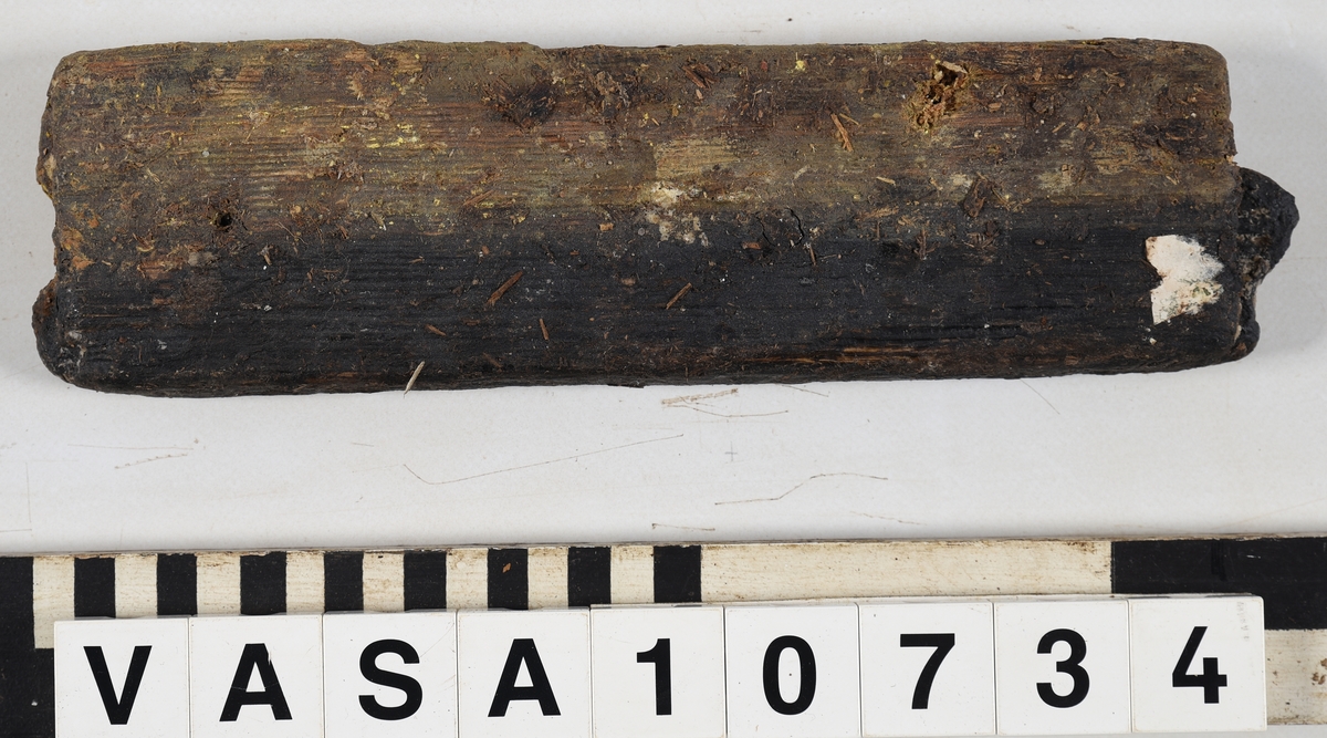 Odekorerad rektangulär bräda med ett spikhål. Tapp på båda ändarna möjlig spont på långsidan. Mycket vittrad yta. Kraftig saltskada (Salt 4) Tapparna avsplittrade.