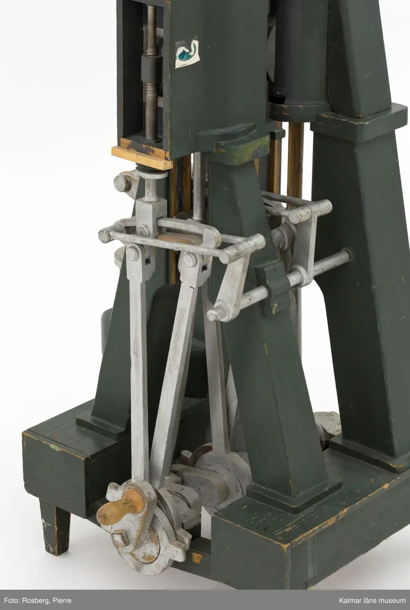 KLM 45865. Modell, maskinmodell. Av trä med detaljer i metall, målad i mörkgrönt och silverfärg. Modellen föreställer någon typ av pump. På ena kortsidan ett handtag för demonstrering av mekaniken. På samma kortsida, nedtill, en del av en lapp: Navigatio ... (troligen Navigationsskolan). Tappkranen till pumpen är lös, eventuellt saknas det någon del.