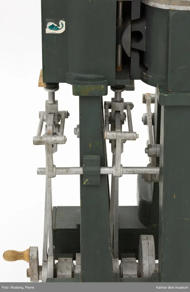 KLM 45865. Modell, maskinmodell. Av trä med detaljer i metall, målad i mörkgrönt och silverfärg. Modellen föreställer någon typ av pump. På ena kortsidan ett handtag för demonstrering av mekaniken. På samma kortsida, nedtill, en del av en lapp: Navigatio ... (troligen Navigationsskolan). Tappkranen till pumpen är lös, eventuellt saknas det någon del.