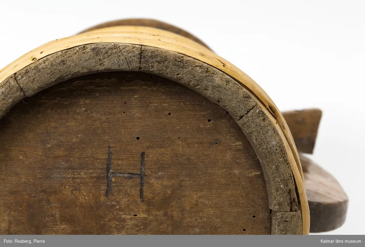 KLM 4090. Stånka. Pipkanna av ek. Laggad med band av vidjor. Svagt konisk med lock och enkelt handtag. Locket försett med handtag och kan stängas med en regel.  Ornering i form av glödritade sicksackband. Utanpå på botten ett H.