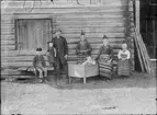 Brita Skötsners familj utanför timmerbyggnad, Rättvik, Dalarna, 1887