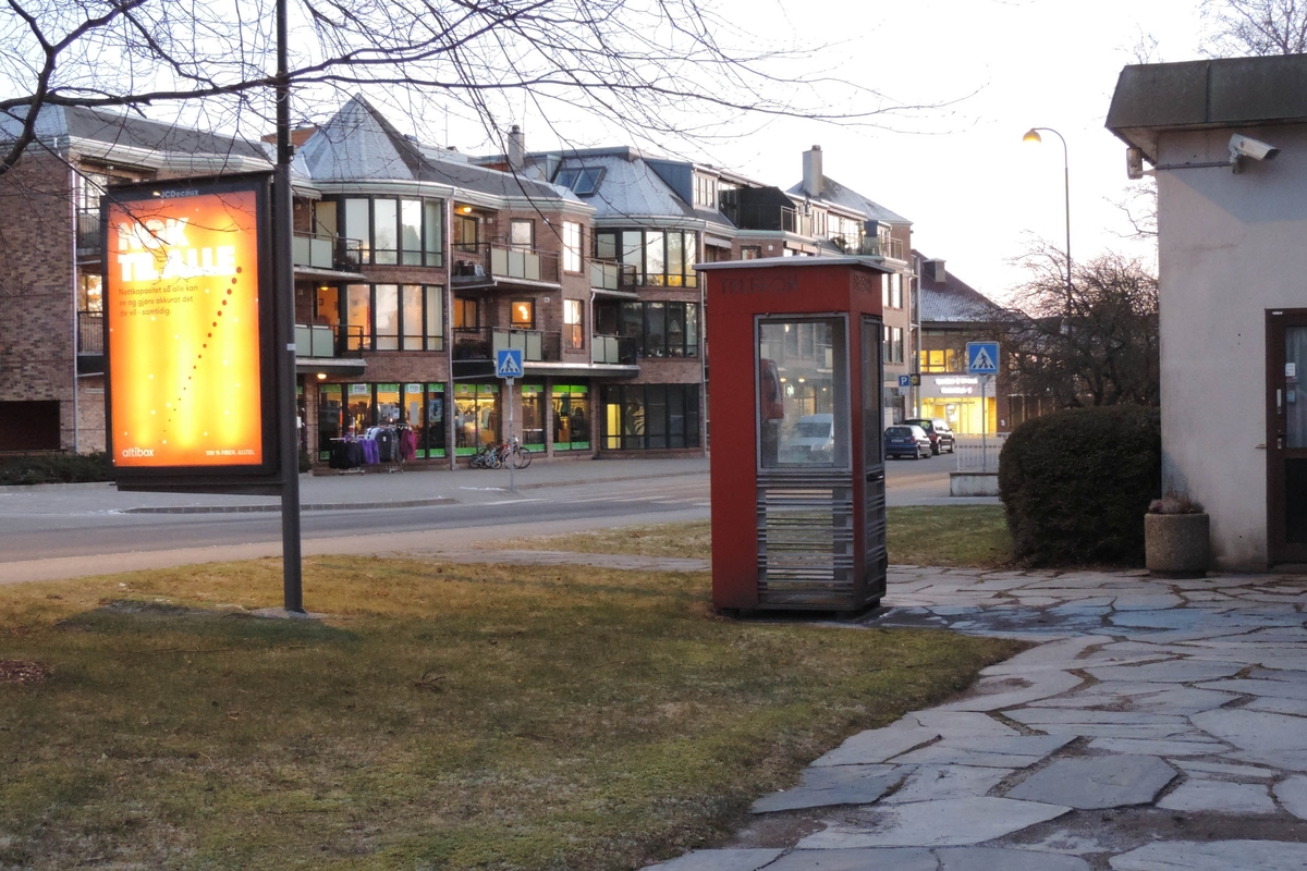 This is the story of how Norway’s most important conversation-space was designed by a young, freshly graduated man from Bergen.

“Norwegian architects are hereby invited…”
In the autumn of 1932, Oslo Telefonanlegginitiated an architectural competition. Finally, Oslo would get its own telephone booth. The city had had so called “talking-stations” from 1885, which in turn were overtaken by automatic telephones 
 only available at selected Narvesen kiosks. The state 
was of the opinion that now was the time to offer the public a better service; public telephone booths open 24/7, like the ones they already had in Sweden and England. But what would they look like, these new telephone booths? What considerations would it
 be necessary to take when designing it? The telegraph board developed a detailed list of demands and restraints: “The booth is intended to be placed outside on the streets and squares and need to be designed so that snow and ice does not hinder the opening and closing of the doors,” they wrote. “To prevent vandalism, theft, uncleanliness etc. inside the booth, it needs to be designed so that from all angles one may see what is going on in there.” Additionally, it would need to withstand storms and bad weather, and “preferably also being whipped by rain mixed with seawater” 

This was not all: The appearance would have to be «pleasing». The booth also needed to be movable, so that it could be taken in to be serviced at Telegrafverket’s main workshops. The reqired material was iron, and the surface was to be spray painted  preferably using car-body paint. There was a requirement for “a writing shelf, a pack shelf, and a suitable place for the telephone catalogue.” Also, there would need to be an illuminated TELEFON  sign, easily visible from all four angles. The total cost for each booth should not exceed 1000 kroner. The first prize for coming up with such a product was 800 kroner.

“Norwegianarchitects are hereby invited to partake in a competition for the design of a telephone booth…”  

The man with the solution
«At some point in 1932, Georg Fredrik sat at a party in Bergen. Maybe he felt a bit lost and forgotten as he often had throughout his life. He retreated to a quiet corner, took out a pencil and strted doodling on a matchbox.  According to my mother, this was how the telephone booth came into being.” In the book “Norges lille røde  historien om telefonkiosken,” Lars Fasting describes his father, the man who is far less known than the iconic architctural structure he left behind. Georg Fredrik Fasting was from Bergen, born into a family of working people and smallholders. One unusual facet of Georg Fredrik was that he was born without ears. His mother made sure he learnt to speak, read and write, 
ut Lars Fasting indicates that his father would seek refuge in drawing when the social challenges became too much to bear. And in the end drawing became his profession. In 1924 he secured a guarantor for a student loan, and started studying to become an a
rchitect at the NTH. Throughout the 1930s he entered several architectural competitions, with drafts produced, according to his son, “after work and in the late hours of the night.”

His efforts were not wasted. Out of 93 entries, with names such as “Flirt”, “Brrr”, “Ring” and “Amor”, the jury selected Fasting’s submission, “RIKS” as the new telephone booth: “The draft shows a strikingly simple solution to the task, technically as well as aesthetically well worked out.”

Taut and provident
Simple and aesthetc are the keywords here. Fasting had designed a booth pointing towards the future, and to modernism. Just how modern it was can be seen by comparing RIKS to the British telephone booth, also designed in the interwar-era. While the British version with it classicistic style is looking back to the heyday of the empire, Fasting’s booth is progressive and functionalistic. Like most Norwegian architects, Fasting broke with the classicistic style of architecture after the Stockholm-exhibition in 1930. “After it, almost all buildings erected in Norway until the German invasion in 1940, were in the functionalistic architectural style,” writes senior curator of architecture at the Norwegian National Museum, Ulf Grønvold, in the book, “Den lille røde”.“TheNorwegian booth is a piece of functionalistic architecture, an asymmetric composition with its roof slab overhanging the word TELEFON, in bold sans seraph lettering,”concludes Ulf Grønvold.

Fashionably red
And it was red. Fasting chose a colour which was part of the modern palette. “A bright red colour, but not as shiny as a signal red, the character of the colour places it among the fashionable colours within functionalism,” states paintings conservator and researcher in NIKU (Norwegian Institute for Cultural Heitage Research), Jon Brænne. In his opinion, Fasting went for visibility without making the booth stand out too much from its surroundings. The original colour was in use up to around 1950, when it changed to signal red. Towards the end of the 1970s the clour was again adjusted towards today’s orangey red.

The design, however, has not changed. RIKS is eighty years and still looks remarkably good. That’s what makes Fasting’s telephone booth a classic  even before it was added to DOCOMOMO’s list over moden icons of design. For Telenor, the telephone booth has served as a pathway into the hearts of the public. For many, Telenor (Televerket) was synonymous with exactly this telephone booth, because this was where one would go to place a call. Having a home
phone was not common until the 1980s. As such the red box became part of the Norwegian everyday and consciousness. The symbol- and publicity value of this is hard to evaluate, but in 2007 it was time to give honour where honour was due, Telenor, in consul
tation with the Directorate for Cultural Heritage, decided to preserve 100 telephone booths for all eternity.

And what about Georg Fredrik Fasting? What happened to him? At the age of 56 an entry in his diary states: «I CAN HEAR». As the first person in th world he had undergone an operation where he had ear canals constructed and eardrums fitted. For the rest of his life, the man behind Norway’s own telephone booth could answer the telephone himself.

Source: Norges lille røde historien om telefonkiosken (2007), issued by The Norwegian Telecom Museum and Telenor Cultural Heritage.