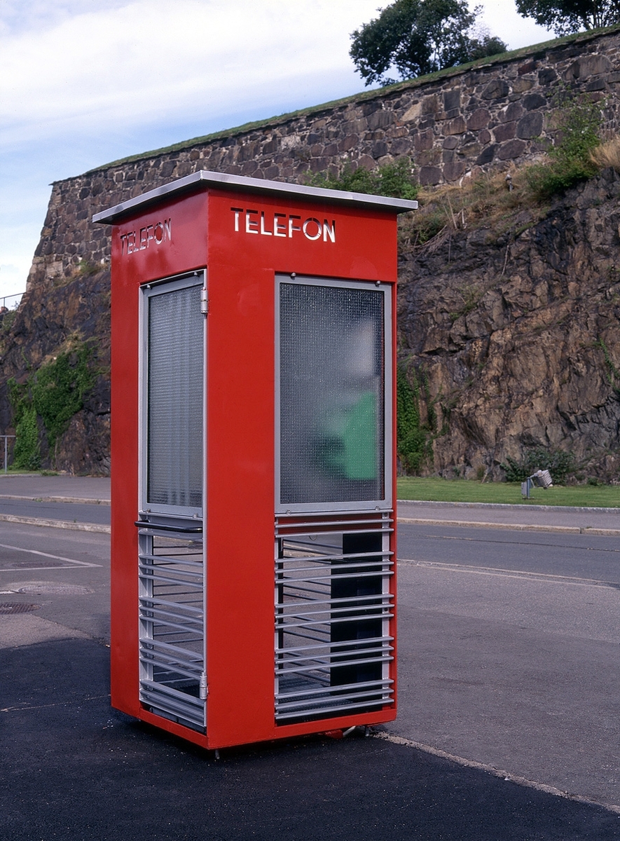 This is the story of how Norway’s most important conversation-space was designed by a young, freshly graduated man from Bergen.

“Norwegian architects are hereby invited…”
In the autumn of 1932, Oslo Telefonanlegginitiated an architectural competition. Finally, Oslo would get its own telephone booth. The city had had so called “talking-stations” from 1885, which in turn were overtaken by automatic telephones 
 only available at selected Narvesen kiosks. The state 
was of the opinion that now was the time to offer the public a better service; public telephone booths open 24/7, like the ones they already had in Sweden and England. But what would they look like, these new telephone booths? What considerations would it
 be necessary to take when designing it? The telegraph board developed a detailed list of demands and restraints: “The booth is intended to be placed outside on the streets and squares and need to be designed so that snow and ice does not hinder the opening and closing of the doors,” they wrote. “To prevent vandalism, theft, uncleanliness etc. inside the booth, it needs to be designed so that from all angles one may see what is going on in there.” Additionally, it would need to withstand storms and bad weather, and “preferably also being whipped by rain mixed with seawater” 

This was not all: The appearance would have to be «pleasing». The booth also needed to be movable, so that it could be taken in to be serviced at Telegrafverket’s main workshops. The reqired material was iron, and the surface was to be spray painted  preferably using car-body paint. There was a requirement for “a writing shelf, a pack shelf, and a suitable place for the telephone catalogue.” Also, there would need to be an illuminated TELEFON  sign, easily visible from all four angles. The total cost for each booth should not exceed 1000 kroner. The first prize for coming up with such a product was 800 kroner.

“Norwegianarchitects are hereby invited to partake in a competition for the design of a telephone booth…”  

The man with the solution
«At some point in 1932, Georg Fredrik sat at a party in Bergen. Maybe he felt a bit lost and forgotten as he often had throughout his life. He retreated to a quiet corner, took out a pencil and strted doodling on a matchbox.  According to my mother, this was how the telephone booth came into being.” In the book “Norges lille røde  historien om telefonkiosken,” Lars Fasting describes his father, the man who is far less known than the iconic architctural structure he left behind. Georg Fredrik Fasting was from Bergen, born into a family of working people and smallholders. One unusual facet of Georg Fredrik was that he was born without ears. His mother made sure he learnt to speak, read and write, 
ut Lars Fasting indicates that his father would seek refuge in drawing when the social challenges became too much to bear. And in the end drawing became his profession. In 1924 he secured a guarantor for a student loan, and started studying to become an a
rchitect at the NTH. Throughout the 1930s he entered several architectural competitions, with drafts produced, according to his son, “after work and in the late hours of the night.”

His efforts were not wasted. Out of 93 entries, with names such as “Flirt”, “Brrr”, “Ring” and “Amor”, the jury selected Fasting’s submission, “RIKS” as the new telephone booth: “The draft shows a strikingly simple solution to the task, technically as well as aesthetically well worked out.”

Taut and provident
Simple and aesthetc are the keywords here. Fasting had designed a booth pointing towards the future, and to modernism. Just how modern it was can be seen by comparing RIKS to the British telephone booth, also designed in the interwar-era. While the British version with it classicistic style is looking back to the heyday of the empire, Fasting’s booth is progressive and functionalistic. Like most Norwegian architects, Fasting broke with the classicistic style of architecture after the Stockholm-exhibition in 1930. “After it, almost all buildings erected in Norway until the German invasion in 1940, were in the functionalistic architectural style,” writes senior curator of architecture at the Norwegian National Museum, Ulf Grønvold, in the book, “Den lille røde”.“TheNorwegian booth is a piece of functionalistic architecture, an asymmetric composition with its roof slab overhanging the word TELEFON, in bold sans seraph lettering,”concludes Ulf Grønvold.

Fashionably red
And it was red. Fasting chose a colour which was part of the modern palette. “A bright red colour, but not as shiny as a signal red, the character of the colour places it among the fashionable colours within functionalism,” states paintings conservator and researcher in NIKU (Norwegian Institute for Cultural Heitage Research), Jon Brænne. In his opinion, Fasting went for visibility without making the booth stand out too much from its surroundings. The original colour was in use up to around 1950, when it changed to signal red. Towards the end of the 1970s the clour was again adjusted towards today’s orangey red.

The design, however, has not changed. RIKS is eighty years and still looks remarkably good. That’s what makes Fasting’s telephone booth a classic  even before it was added to DOCOMOMO’s list over moden icons of design. For Telenor, the telephone booth has served as a pathway into the hearts of the public. For many, Telenor (Televerket) was synonymous with exactly this telephone booth, because this was where one would go to place a call. Having a home
phone was not common until the 1980s. As such the red box became part of the Norwegian everyday and consciousness. The symbol- and publicity value of this is hard to evaluate, but in 2007 it was time to give honour where honour was due, Telenor, in consul
tation with the Directorate for Cultural Heritage, decided to preserve 100 telephone booths for all eternity.

And what about Georg Fredrik Fasting? What happened to him? At the age of 56 an entry in his diary states: «I CAN HEAR». As the first person in th world he had undergone an operation where he had ear canals constructed and eardrums fitted. For the rest of his life, the man behind Norway’s own telephone booth could answer the telephone himself.

Source: Norges lille røde historien om telefonkiosken (2007), issued by The Norwegian Telecom Museum and Telenor Cultural Heritage.