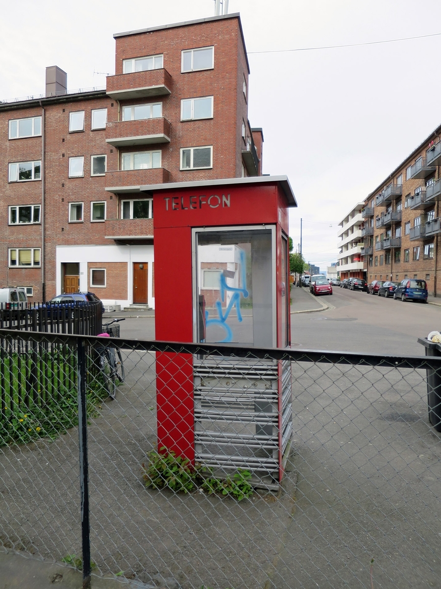 This is the story of how Norway’s most important conversation-space was designed by a young, freshly graduated man from Bergen.

“Norwegian architects are hereby invited…”
In the autumn of 1932, Oslo Telefonanlegginitiated an architectural competition. Finally, Oslo would get its own telephone booth. The city had had so called “talking-stations” from 1885, which in turn were overtaken by automatic telephones 
 only available at selected Narvesen kiosks. The state 
was of the opinion that now was the time to offer the public a better service; public telephone booths open 24/7, like the ones they already had in Sweden and England. But what would they look like, these new telephone booths? What considerations would it
 be necessary to take when designing it? The telegraph board developed a detailed list of demands and restraints: “The booth is intended to be placed outside on the streets and squares and need to be designed so that snow and ice does not hinder the opening and closing of the doors,” they wrote. “To prevent vandalism, theft, uncleanliness etc. inside the booth, it needs to be designed so that from all angles one may see what is going on in there.” Additionally, it would need to withstand storms and bad weather, and “preferably also being whipped by rain mixed with seawater” 

This was not all: The appearance would have to be «pleasing». The booth also needed to be movable, so that it could be taken in to be serviced at Telegrafverket’s main workshops. The reqired material was iron, and the surface was to be spray painted  preferably using car-body paint. There was a requirement for “a writing shelf, a pack shelf, and a suitable place for the telephone catalogue.” Also, there would need to be an illuminated TELEFON  sign, easily visible from all four angles. The total cost for each booth should not exceed 1000 kroner. The first prize for coming up with such a product was 800 kroner.

“Norwegianarchitects are hereby invited to partake in a competition for the design of a telephone booth…”  

The man with the solution
«At some point in 1932, Georg Fredrik sat at a party in Bergen. Maybe he felt a bit lost and forgotten as he often had throughout his life. He retreated to a quiet corner, took out a pencil and strted doodling on a matchbox.  According to my mother, this was how the telephone booth came into being.” In the book “Norges lille røde  historien om telefonkiosken,” Lars Fasting describes his father, the man who is far less known than the iconic architctural structure he left behind. Georg Fredrik Fasting was from Bergen, born into a family of working people and smallholders. One unusual facet of Georg Fredrik was that he was born without ears. His mother made sure he learnt to speak, read and write, 
ut Lars Fasting indicates that his father would seek refuge in drawing when the social challenges became too much to bear. And in the end drawing became his profession. In 1924 he secured a guarantor for a student loan, and started studying to become an a
rchitect at the NTH. Throughout the 1930s he entered several architectural competitions, with drafts produced, according to his son, “after work and in the late hours of the night.”

His efforts were not wasted. Out of 93 entries, with names such as “Flirt”, “Brrr”, “Ring” and “Amor”, the jury selected Fasting’s submission, “RIKS” as the new telephone booth: “The draft shows a strikingly simple solution to the task, technically as well as aesthetically well worked out.”

Taut and provident
Simple and aesthetc are the keywords here. Fasting had designed a booth pointing towards the future, and to modernism. Just how modern it was can be seen by comparing RIKS to the British telephone booth, also designed in the interwar-era. While the British version with it classicistic style is looking back to the heyday of the empire, Fasting’s booth is progressive and functionalistic. Like most Norwegian architects, Fasting broke with the classicistic style of architecture after the Stockholm-exhibition in 1930. “After it, almost all buildings erected in Norway until the German invasion in 1940, were in the functionalistic architectural style,” writes senior curator of architecture at the Norwegian National Museum, Ulf Grønvold, in the book, “Den lille røde”.“TheNorwegian booth is a piece of functionalistic architecture, an asymmetric composition with its roof slab overhanging the word TELEFON, in bold sans seraph lettering,”concludes Ulf Grønvold.

Fashionably red
And it was red. Fasting chose a colour which was part of the modern palette. “A bright red colour, but not as shiny as a signal red, the character of the colour places it among the fashionable colours within functionalism,” states paintings conservator and researcher in NIKU (Norwegian Institute for Cultural Heitage Research), Jon Brænne. In his opinion, Fasting went for visibility without making the booth stand out too much from its surroundings. The original colour was in use up to around 1950, when it changed to signal red. Towards the end of the 1970s the clour was again adjusted towards today’s orangey red.

The design, however, has not changed. RIKS is eighty years and still looks remarkably good. That’s what makes Fasting’s telephone booth a classic  even before it was added to DOCOMOMO’s list over moden icons of design. For Telenor, the telephone booth has served as a pathway into the hearts of the public. For many, Telenor (Televerket) was synonymous with exactly this telephone booth, because this was where one would go to place a call. Having a home
phone was not common until the 1980s. As such the red box became part of the Norwegian everyday and consciousness. The symbol- and publicity value of this is hard to evaluate, but in 2007 it was time to give honour where honour was due, Telenor, in consul
tation with the Directorate for Cultural Heritage, decided to preserve 100 telephone booths for all eternity.

And what about Georg Fredrik Fasting? What happened to him? At the age of 56 an entry in his diary states: «I CAN HEAR». As the first person in th world he had undergone an operation where he had ear canals constructed and eardrums fitted. For the rest of his life, the man behind Norway’s own telephone booth could answer the telephone himself.

Source: Norges lille røde historien om telefonkiosken (2007), issued by The Norwegian Telecom Museum and Telenor Cultural Heritage.