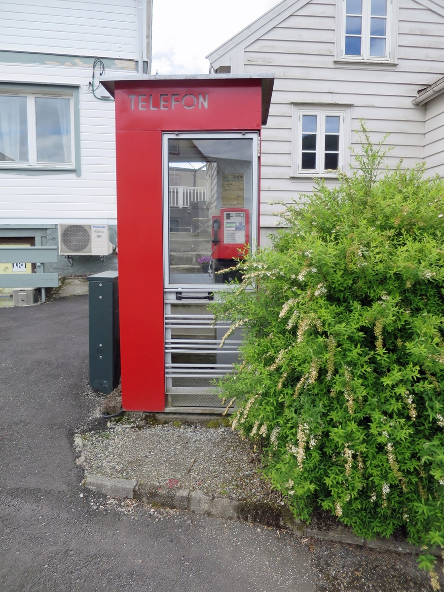 This is the story of how Norway’s most important conversation-space was designed by a young, freshly graduated man from Bergen.

“Norwegian architects are hereby invited…”
In the autumn of 1932, Oslo Telefonanlegginitiated an architectural competition. Finally, Oslo would get its own telephone booth. The city had had so called “talking-stations” from 1885, which in turn were overtaken by automatic telephones 
 only available at selected Narvesen kiosks. The state 
was of the opinion that now was the time to offer the public a better service; public telephone booths open 24/7, like the ones they already had in Sweden and England. But what would they look like, these new telephone booths? What considerations would it
 be necessary to take when designing it? The telegraph board developed a detailed list of demands and restraints: “The booth is intended to be placed outside on the streets and squares and need to be designed so that snow and ice does not hinder the opening and closing of the doors,” they wrote. “To prevent vandalism, theft, uncleanliness etc. inside the booth, it needs to be designed so that from all angles one may see what is going on in there.” Additionally, it would need to withstand storms and bad weather, and “preferably also being whipped by rain mixed with seawater” 

This was not all: The appearance would have to be «pleasing». The booth also needed to be movable, so that it could be taken in to be serviced at Telegrafverket’s main workshops. The reqired material was iron, and the surface was to be spray painted  preferably using car-body paint. There was a requirement for “a writing shelf, a pack shelf, and a suitable place for the telephone catalogue.” Also, there would need to be an illuminated TELEFON  sign, easily visible from all four angles. The total cost for each booth should not exceed 1000 kroner. The first prize for coming up with such a product was 800 kroner.

“Norwegianarchitects are hereby invited to partake in a competition for the design of a telephone booth…”  

The man with the solution
«At some point in 1932, Georg Fredrik sat at a party in Bergen. Maybe he felt a bit lost and forgotten as he often had throughout his life. He retreated to a quiet corner, took out a pencil and strted doodling on a matchbox.  According to my mother, this was how the telephone booth came into being.” In the book “Norges lille røde  historien om telefonkiosken,” Lars Fasting describes his father, the man who is far less known than the iconic architctural structure he left behind. Georg Fredrik Fasting was from Bergen, born into a family of working people and smallholders. One unusual facet of Georg Fredrik was that he was born without ears. His mother made sure he learnt to speak, read and write, 
ut Lars Fasting indicates that his father would seek refuge in drawing when the social challenges became too much to bear. And in the end drawing became his profession. In 1924 he secured a guarantor for a student loan, and started studying to become an a
rchitect at the NTH. Throughout the 1930s he entered several architectural competitions, with drafts produced, according to his son, “after work and in the late hours of the night.”

His efforts were not wasted. Out of 93 entries, with names such as “Flirt”, “Brrr”, “Ring” and “Amor”, the jury selected Fasting’s submission, “RIKS” as the new telephone booth: “The draft shows a strikingly simple solution to the task, technically as well as aesthetically well worked out.”

Taut and provident
Simple and aesthetc are the keywords here. Fasting had designed a booth pointing towards the future, and to modernism. Just how modern it was can be seen by comparing RIKS to the British telephone booth, also designed in the interwar-era. While the British version with it classicistic style is looking back to the heyday of the empire, Fasting’s booth is progressive and functionalistic. Like most Norwegian architects, Fasting broke with the classicistic style of architecture after the Stockholm-exhibition in 1930. “After it, almost all buildings erected in Norway until the German invasion in 1940, were in the functionalistic architectural style,” writes senior curator of architecture at the Norwegian National Museum, Ulf Grønvold, in the book, “Den lille røde”.“TheNorwegian booth is a piece of functionalistic architecture, an asymmetric composition with its roof slab overhanging the word TELEFON, in bold sans seraph lettering,”concludes Ulf Grønvold.

Fashionably red
And it was red. Fasting chose a colour which was part of the modern palette. “A bright red colour, but not as shiny as a signal red, the character of the colour places it among the fashionable colours within functionalism,” states paintings conservator and researcher in NIKU (Norwegian Institute for Cultural Heitage Research), Jon Brænne. In his opinion, Fasting went for visibility without making the booth stand out too much from its surroundings. The original colour was in use up to around 1950, when it changed to signal red. Towards the end of the 1970s the clour was again adjusted towards today’s orangey red.

The design, however, has not changed. RIKS is eighty years and still looks remarkably good. That’s what makes Fasting’s telephone booth a classic  even before it was added to DOCOMOMO’s list over moden icons of design. For Telenor, the telephone booth has served as a pathway into the hearts of the public. For many, Telenor (Televerket) was synonymous with exactly this telephone booth, because this was where one would go to place a call. Having a home
phone was not common until the 1980s. As such the red box became part of the Norwegian everyday and consciousness. The symbol- and publicity value of this is hard to evaluate, but in 2007 it was time to give honour where honour was due, Telenor, in consul
tation with the Directorate for Cultural Heritage, decided to preserve 100 telephone booths for all eternity.

And what about Georg Fredrik Fasting? What happened to him? At the age of 56 an entry in his diary states: «I CAN HEAR». As the first person in th world he had undergone an operation where he had ear canals constructed and eardrums fitted. For the rest of his life, the man behind Norway’s own telephone booth could answer the telephone himself.

Source: Norges lille røde historien om telefonkiosken (2007), issued by The Norwegian Telecom Museum and Telenor Cultural Heritage.