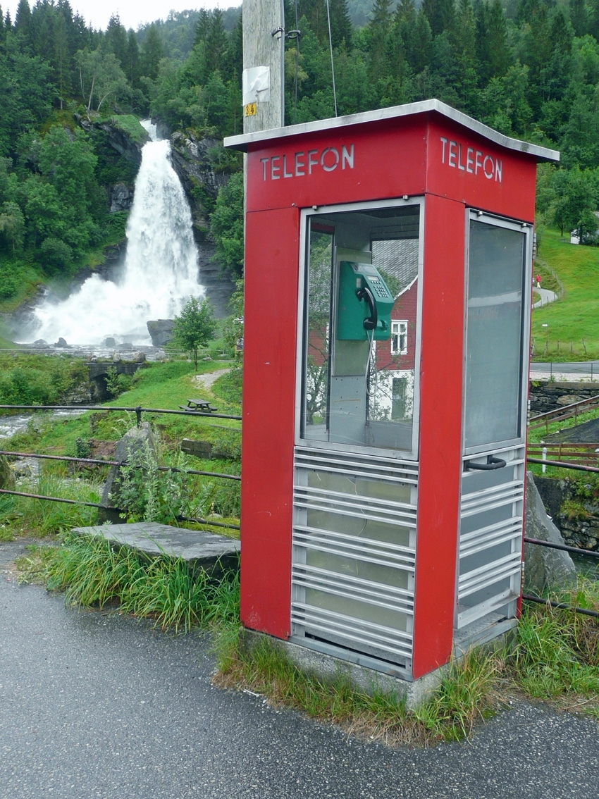 This is the story of how Norway’s most important conversation-space was designed by a young, freshly graduated man from Bergen.

“Norwegian architects are hereby invited…”
In the autumn of 1932, Oslo Telefonanlegginitiated an architectural competition. Finally, Oslo would get its own telephone booth. The city had had so called “talking-stations” from 1885, which in turn were overtaken by automatic telephones 
 only available at selected Narvesen kiosks. The state 
was of the opinion that now was the time to offer the public a better service; public telephone booths open 24/7, like the ones they already had in Sweden and England. But what would they look like, these new telephone booths? What considerations would it
 be necessary to take when designing it? The telegraph board developed a detailed list of demands and restraints: “The booth is intended to be placed outside on the streets and squares and need to be designed so that snow and ice does not hinder the opening and closing of the doors,” they wrote. “To prevent vandalism, theft, uncleanliness etc. inside the booth, it needs to be designed so that from all angles one may see what is going on in there.” Additionally, it would need to withstand storms and bad weather, and “preferably also being whipped by rain mixed with seawater” 

This was not all: The appearance would have to be «pleasing». The booth also needed to be movable, so that it could be taken in to be serviced at Telegrafverket’s main workshops. The reqired material was iron, and the surface was to be spray painted  preferably using car-body paint. There was a requirement for “a writing shelf, a pack shelf, and a suitable place for the telephone catalogue.” Also, there would need to be an illuminated TELEFON  sign, easily visible from all four angles. The total cost for each booth should not exceed 1000 kroner. The first prize for coming up with such a product was 800 kroner.

“Norwegianarchitects are hereby invited to partake in a competition for the design of a telephone booth…”  

The man with the solution
«At some point in 1932, Georg Fredrik sat at a party in Bergen. Maybe he felt a bit lost and forgotten as he often had throughout his life. He retreated to a quiet corner, took out a pencil and strted doodling on a matchbox.  According to my mother, this was how the telephone booth came into being.” In the book “Norges lille røde  historien om telefonkiosken,” Lars Fasting describes his father, the man who is far less known than the iconic architctural structure he left behind. Georg Fredrik Fasting was from Bergen, born into a family of working people and smallholders. One unusual facet of Georg Fredrik was that he was born without ears. His mother made sure he learnt to speak, read and write, 
ut Lars Fasting indicates that his father would seek refuge in drawing when the social challenges became too much to bear. And in the end drawing became his profession. In 1924 he secured a guarantor for a student loan, and started studying to become an a
rchitect at the NTH. Throughout the 1930s he entered several architectural competitions, with drafts produced, according to his son, “after work and in the late hours of the night.”

His efforts were not wasted. Out of 93 entries, with names such as “Flirt”, “Brrr”, “Ring” and “Amor”, the jury selected Fasting’s submission, “RIKS” as the new telephone booth: “The draft shows a strikingly simple solution to the task, technically as well as aesthetically well worked out.”

Taut and provident
Simple and aesthetc are the keywords here. Fasting had designed a booth pointing towards the future, and to modernism. Just how modern it was can be seen by comparing RIKS to the British telephone booth, also designed in the interwar-era. While the British version with it classicistic style is looking back to the heyday of the empire, Fasting’s booth is progressive and functionalistic. Like most Norwegian architects, Fasting broke with the classicistic style of architecture after the Stockholm-exhibition in 1930. “After it, almost all buildings erected in Norway until the German invasion in 1940, were in the functionalistic architectural style,” writes senior curator of architecture at the Norwegian National Museum, Ulf Grønvold, in the book, “Den lille røde”.“TheNorwegian booth is a piece of functionalistic architecture, an asymmetric composition with its roof slab overhanging the word TELEFON, in bold sans seraph lettering,”concludes Ulf Grønvold.

Fashionably red
And it was red. Fasting chose a colour which was part of the modern palette. “A bright red colour, but not as shiny as a signal red, the character of the colour places it among the fashionable colours within functionalism,” states paintings conservator and researcher in NIKU (Norwegian Institute for Cultural Heitage Research), Jon Brænne. In his opinion, Fasting went for visibility without making the booth stand out too much from its surroundings. The original colour was in use up to around 1950, when it changed to signal red. Towards the end of the 1970s the clour was again adjusted towards today’s orangey red.

The design, however, has not changed. RIKS is eighty years and still looks remarkably good. That’s what makes Fasting’s telephone booth a classic  even before it was added to DOCOMOMO’s list over moden icons of design. For Telenor, the telephone booth has served as a pathway into the hearts of the public. For many, Telenor (Televerket) was synonymous with exactly this telephone booth, because this was where one would go to place a call. Having a home
phone was not common until the 1980s. As such the red box became part of the Norwegian everyday and consciousness. The symbol- and publicity value of this is hard to evaluate, but in 2007 it was time to give honour where honour was due, Telenor, in consul
tation with the Directorate for Cultural Heritage, decided to preserve 100 telephone booths for all eternity.

And what about Georg Fredrik Fasting? What happened to him? At the age of 56 an entry in his diary states: «I CAN HEAR». As the first person in th world he had undergone an operation where he had ear canals constructed and eardrums fitted. For the rest of his life, the man behind Norway’s own telephone booth could answer the telephone himself.

Source: Norges lille røde historien om telefonkiosken (2007), issued by The Norwegian Telecom Museum and Telenor Cultural Heritage.