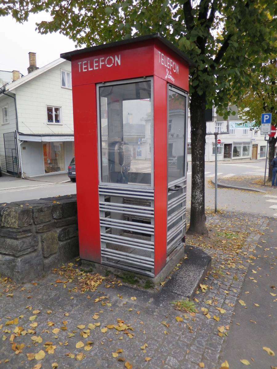 This is the story of how Norway’s most important conversation-space was designed by a young, freshly graduated man from Bergen.

“Norwegian architects are hereby invited…”
In the autumn of 1932, Oslo Telefonanlegginitiated an architectural competition. Finally, Oslo would get its own telephone booth. The city had had so called “talking-stations” from 1885, which in turn were overtaken by automatic telephones 
 only available at selected Narvesen kiosks. The state 
was of the opinion that now was the time to offer the public a better service; public telephone booths open 24/7, like the ones they already had in Sweden and England. But what would they look like, these new telephone booths? What considerations would it
 be necessary to take when designing it? The telegraph board developed a detailed list of demands and restraints: “The booth is intended to be placed outside on the streets and squares and need to be designed so that snow and ice does not hinder the opening and closing of the doors,” they wrote. “To prevent vandalism, theft, uncleanliness etc. inside the booth, it needs to be designed so that from all angles one may see what is going on in there.” Additionally, it would need to withstand storms and bad weather, and “preferably also being whipped by rain mixed with seawater” 

This was not all: The appearance would have to be «pleasing». The booth also needed to be movable, so that it could be taken in to be serviced at Telegrafverket’s main workshops. The reqired material was iron, and the surface was to be spray painted  preferably using car-body paint. There was a requirement for “a writing shelf, a pack shelf, and a suitable place for the telephone catalogue.” Also, there would need to be an illuminated TELEFON  sign, easily visible from all four angles. The total cost for each booth should not exceed 1000 kroner. The first prize for coming up with such a product was 800 kroner.

“Norwegianarchitects are hereby invited to partake in a competition for the design of a telephone booth…”  

The man with the solution
«At some point in 1932, Georg Fredrik sat at a party in Bergen. Maybe he felt a bit lost and forgotten as he often had throughout his life. He retreated to a quiet corner, took out a pencil and strted doodling on a matchbox.  According to my mother, this was how the telephone booth came into being.” In the book “Norges lille røde  historien om telefonkiosken,” Lars Fasting describes his father, the man who is far less known than the iconic architctural structure he left behind. Georg Fredrik Fasting was from Bergen, born into a family of working people and smallholders. One unusual facet of Georg Fredrik was that he was born without ears. His mother made sure he learnt to speak, read and write, 
ut Lars Fasting indicates that his father would seek refuge in drawing when the social challenges became too much to bear. And in the end drawing became his profession. In 1924 he secured a guarantor for a student loan, and started studying to become an a
rchitect at the NTH. Throughout the 1930s he entered several architectural competitions, with drafts produced, according to his son, “after work and in the late hours of the night.”

His efforts were not wasted. Out of 93 entries, with names such as “Flirt”, “Brrr”, “Ring” and “Amor”, the jury selected Fasting’s submission, “RIKS” as the new telephone booth: “The draft shows a strikingly simple solution to the task, technically as well as aesthetically well worked out.”

Taut and provident
Simple and aesthetc are the keywords here. Fasting had designed a booth pointing towards the future, and to modernism. Just how modern it was can be seen by comparing RIKS to the British telephone booth, also designed in the interwar-era. While the British version with it classicistic style is looking back to the heyday of the empire, Fasting’s booth is progressive and functionalistic. Like most Norwegian architects, Fasting broke with the classicistic style of architecture after the Stockholm-exhibition in 1930. “After it, almost all buildings erected in Norway until the German invasion in 1940, were in the functionalistic architectural style,” writes senior curator of architecture at the Norwegian National Museum, Ulf Grønvold, in the book, “Den lille røde”.“TheNorwegian booth is a piece of functionalistic architecture, an asymmetric composition with its roof slab overhanging the word TELEFON, in bold sans seraph lettering,”concludes Ulf Grønvold.

Fashionably red
And it was red. Fasting chose a colour which was part of the modern palette. “A bright red colour, but not as shiny as a signal red, the character of the colour places it among the fashionable colours within functionalism,” states paintings conservator and researcher in NIKU (Norwegian Institute for Cultural Heitage Research), Jon Brænne. In his opinion, Fasting went for visibility without making the booth stand out too much from its surroundings. The original colour was in use up to around 1950, when it changed to signal red. Towards the end of the 1970s the clour was again adjusted towards today’s orangey red.

The design, however, has not changed. RIKS is eighty years and still looks remarkably good. That’s what makes Fasting’s telephone booth a classic  even before it was added to DOCOMOMO’s list over moden icons of design. For Telenor, the telephone booth has served as a pathway into the hearts of the public. For many, Telenor (Televerket) was synonymous with exactly this telephone booth, because this was where one would go to place a call. Having a home
phone was not common until the 1980s. As such the red box became part of the Norwegian everyday and consciousness. The symbol- and publicity value of this is hard to evaluate, but in 2007 it was time to give honour where honour was due, Telenor, in consul
tation with the Directorate for Cultural Heritage, decided to preserve 100 telephone booths for all eternity.

And what about Georg Fredrik Fasting? What happened to him? At the age of 56 an entry in his diary states: «I CAN HEAR». As the first person in th world he had undergone an operation where he had ear canals constructed and eardrums fitted. For the rest of his life, the man behind Norway’s own telephone booth could answer the telephone himself.

Source: Norges lille røde historien om telefonkiosken (2007), issued by The Norwegian Telecom Museum and Telenor Cultural Heritage.