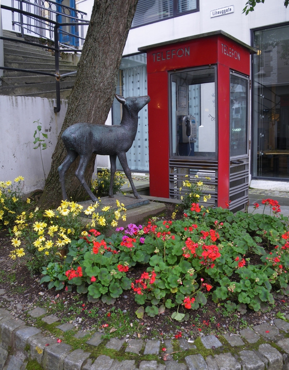 This is the story of how Norway’s most important conversation-space was designed by a young, freshly graduated man from Bergen.

“Norwegian architects are hereby invited…”
In the autumn of 1932, Oslo Telefonanlegginitiated an architectural competition. Finally, Oslo would get its own telephone booth. The city had had so called “talking-stations” from 1885, which in turn were overtaken by automatic telephones 
 only available at selected Narvesen kiosks. The state 
was of the opinion that now was the time to offer the public a better service; public telephone booths open 24/7, like the ones they already had in Sweden and England. But what would they look like, these new telephone booths? What considerations would it
 be necessary to take when designing it? The telegraph board developed a detailed list of demands and restraints: “The booth is intended to be placed outside on the streets and squares and need to be designed so that snow and ice does not hinder the opening and closing of the doors,” they wrote. “To prevent vandalism, theft, uncleanliness etc. inside the booth, it needs to be designed so that from all angles one may see what is going on in there.” Additionally, it would need to withstand storms and bad weather, and “preferably also being whipped by rain mixed with seawater” 

This was not all: The appearance would have to be «pleasing». The booth also needed to be movable, so that it could be taken in to be serviced at Telegrafverket’s main workshops. The reqired material was iron, and the surface was to be spray painted  preferably using car-body paint. There was a requirement for “a writing shelf, a pack shelf, and a suitable place for the telephone catalogue.” Also, there would need to be an illuminated TELEFON  sign, easily visible from all four angles. The total cost for each booth should not exceed 1000 kroner. The first prize for coming up with such a product was 800 kroner.

“Norwegianarchitects are hereby invited to partake in a competition for the design of a telephone booth…”  

The man with the solution
«At some point in 1932, Georg Fredrik sat at a party in Bergen. Maybe he felt a bit lost and forgotten as he often had throughout his life. He retreated to a quiet corner, took out a pencil and strted doodling on a matchbox.  According to my mother, this was how the telephone booth came into being.” In the book “Norges lille røde  historien om telefonkiosken,” Lars Fasting describes his father, the man who is far less known than the iconic architctural structure he left behind. Georg Fredrik Fasting was from Bergen, born into a family of working people and smallholders. One unusual facet of Georg Fredrik was that he was born without ears. His mother made sure he learnt to speak, read and write, 
ut Lars Fasting indicates that his father would seek refuge in drawing when the social challenges became too much to bear. And in the end drawing became his profession. In 1924 he secured a guarantor for a student loan, and started studying to become an a
rchitect at the NTH. Throughout the 1930s he entered several architectural competitions, with drafts produced, according to his son, “after work and in the late hours of the night.”

His efforts were not wasted. Out of 93 entries, with names such as “Flirt”, “Brrr”, “Ring” and “Amor”, the jury selected Fasting’s submission, “RIKS” as the new telephone booth: “The draft shows a strikingly simple solution to the task, technically as well as aesthetically well worked out.”

Taut and provident
Simple and aesthetc are the keywords here. Fasting had designed a booth pointing towards the future, and to modernism. Just how modern it was can be seen by comparing RIKS to the British telephone booth, also designed in the interwar-era. While the British version with it classicistic style is looking back to the heyday of the empire, Fasting’s booth is progressive and functionalistic. Like most Norwegian architects, Fasting broke with the classicistic style of architecture after the Stockholm-exhibition in 1930. “After it, almost all buildings erected in Norway until the German invasion in 1940, were in the functionalistic architectural style,” writes senior curator of architecture at the Norwegian National Museum, Ulf Grønvold, in the book, “Den lille røde”.“TheNorwegian booth is a piece of functionalistic architecture, an asymmetric composition with its roof slab overhanging the word TELEFON, in bold sans seraph lettering,”concludes Ulf Grønvold.

Fashionably red
And it was red. Fasting chose a colour which was part of the modern palette. “A bright red colour, but not as shiny as a signal red, the character of the colour places it among the fashionable colours within functionalism,” states paintings conservator and researcher in NIKU (Norwegian Institute for Cultural Heitage Research), Jon Brænne. In his opinion, Fasting went for visibility without making the booth stand out too much from its surroundings. The original colour was in use up to around 1950, when it changed to signal red. Towards the end of the 1970s the clour was again adjusted towards today’s orangey red.

The design, however, has not changed. RIKS is eighty years and still looks remarkably good. That’s what makes Fasting’s telephone booth a classic  even before it was added to DOCOMOMO’s list over moden icons of design. For Telenor, the telephone booth has served as a pathway into the hearts of the public. For many, Telenor (Televerket) was synonymous with exactly this telephone booth, because this was where one would go to place a call. Having a home
phone was not common until the 1980s. As such the red box became part of the Norwegian everyday and consciousness. The symbol- and publicity value of this is hard to evaluate, but in 2007 it was time to give honour where honour was due, Telenor, in consul
tation with the Directorate for Cultural Heritage, decided to preserve 100 telephone booths for all eternity.

And what about Georg Fredrik Fasting? What happened to him? At the age of 56 an entry in his diary states: «I CAN HEAR». As the first person in th world he had undergone an operation where he had ear canals constructed and eardrums fitted. For the rest of his life, the man behind Norway’s own telephone booth could answer the telephone himself.

Source: Norges lille røde historien om telefonkiosken (2007), issued by The Norwegian Telecom Museum and Telenor Cultural Heritage.