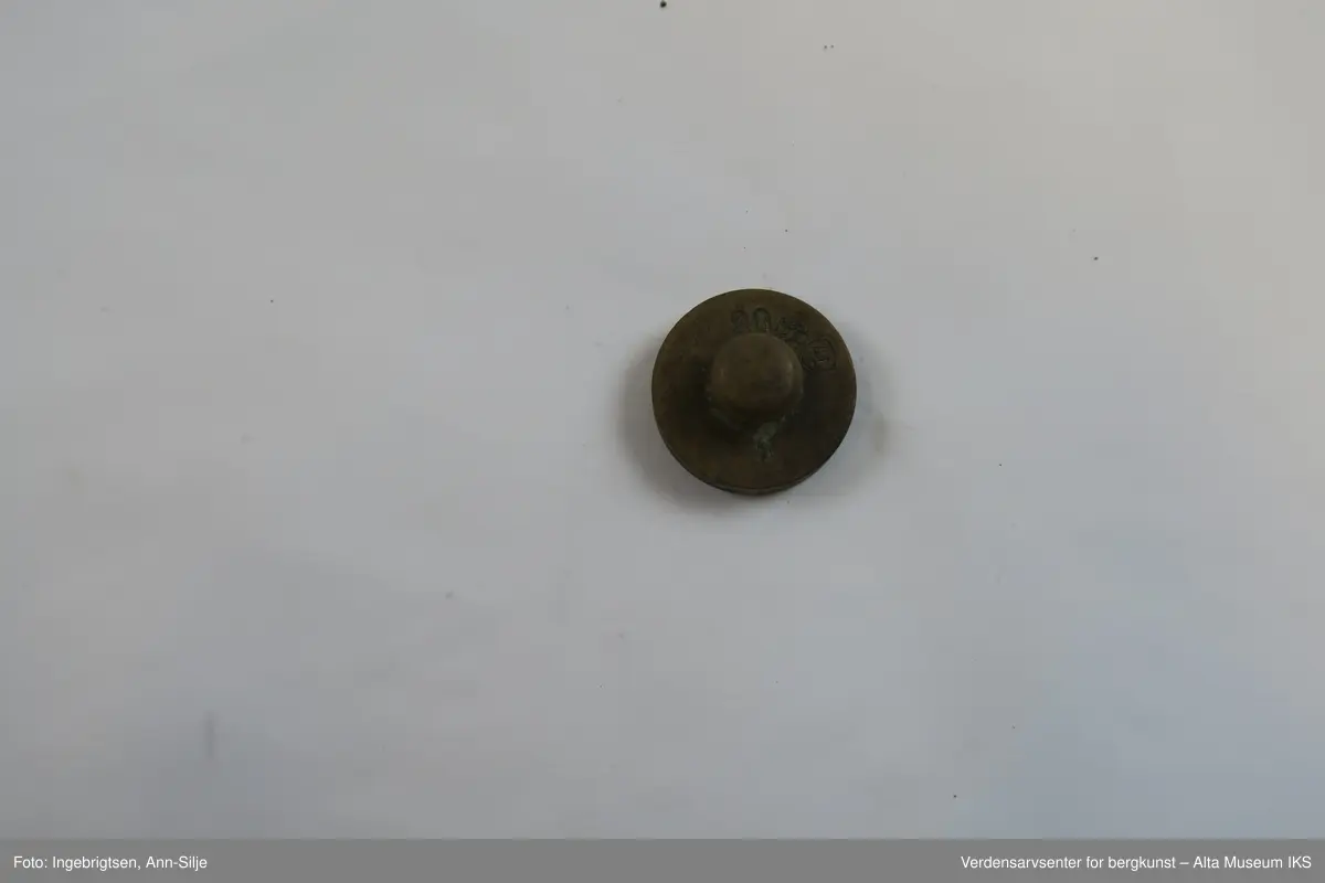 Rektangulær trebit, med hull tilpasset ulike loddstørrelser. Det er 7 lodd: 2 stk. 10 gram, 1 stk. 20 gram, 1 st. 50 gram, 2 stk. 100 gram og 1 stk. 200 gram. Alle loddene er sylinderformet med knott på toppen. Loddene varierer i størrelse: de minste er 2 cm i diameter og 1 cm i høyde, mens den største er 4 cm i diameter og 2,8 cm i høyde.