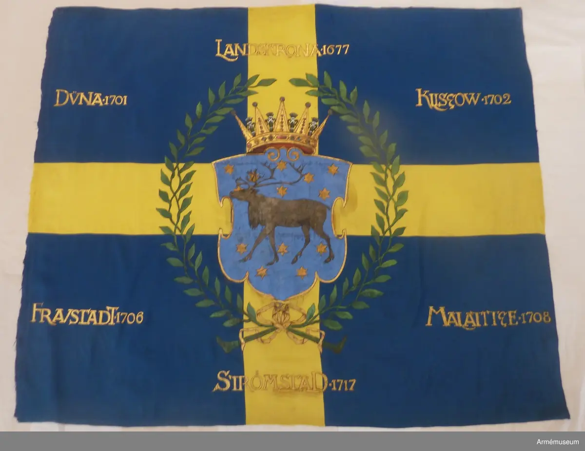 Korsfana med krönt sköld med renen omgiven av stjärnorna. Skölden är innesluten i en lagerkrans. Segernamn.