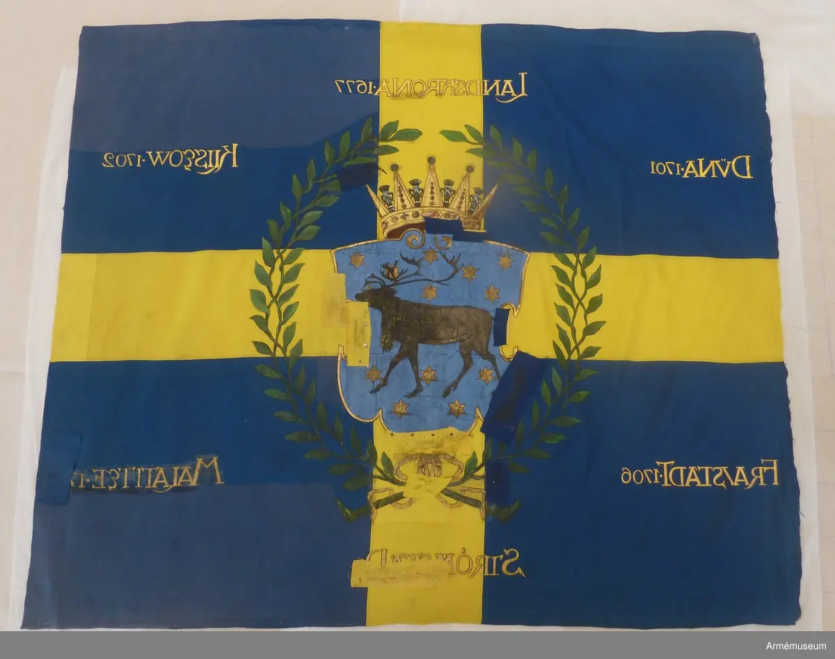 Korsfana med krönt sköld med renen omgiven av stjärnorna. Skölden är innesluten i en lagerkrans. Segernamn.